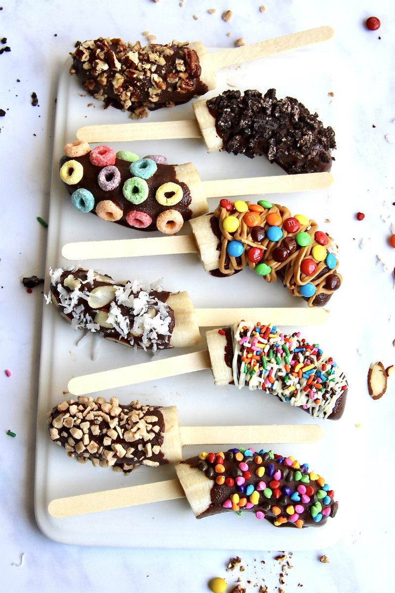 A display of Chocolate Covered Frozen Banana Pops with different toppings