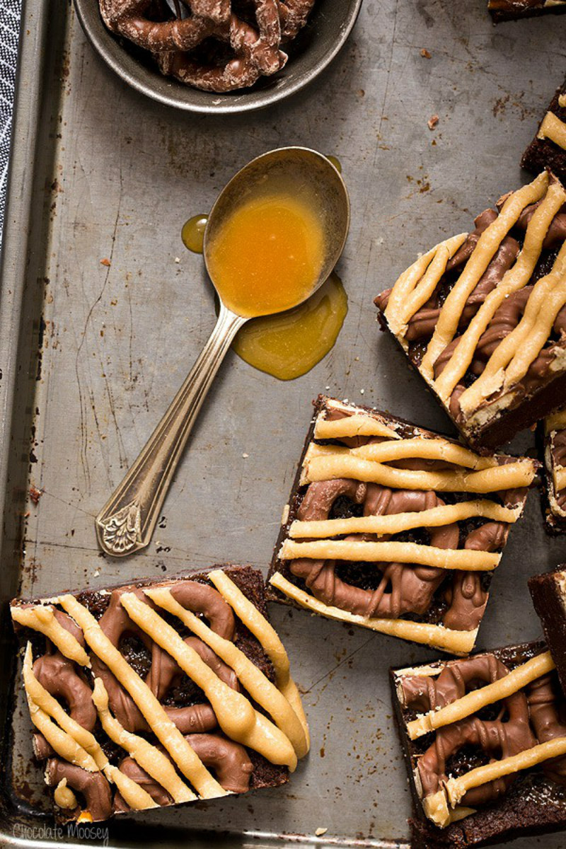 chocolate covered pretzel caramel brownies with a spoonful of caramel on baking sheet