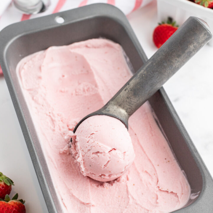 scooping strawberry ice cream out of a container