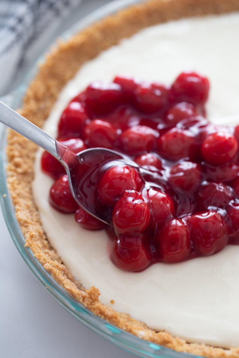 spooning cherry pie filling onto pie