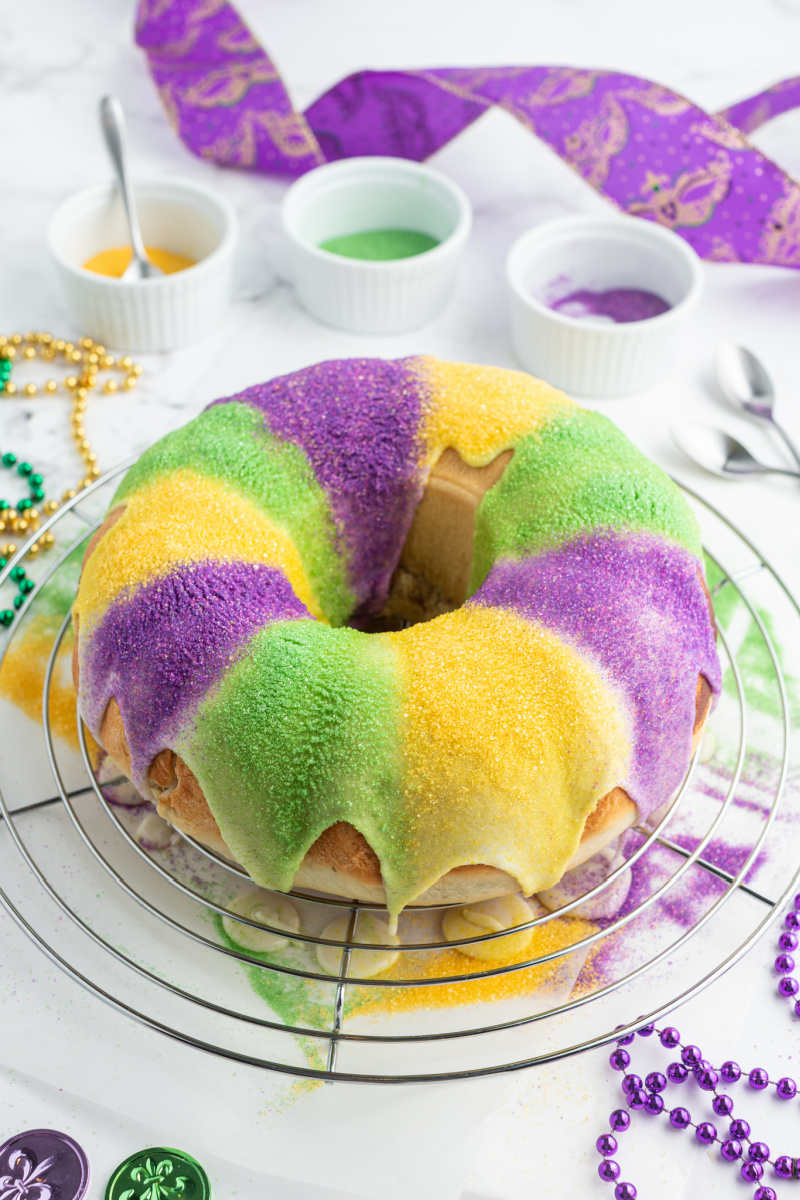 adding frosting and colored sugars to king cake