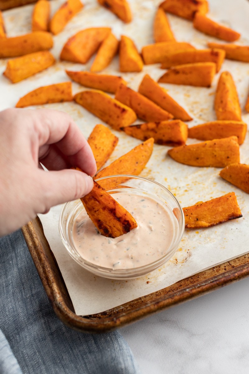 dipping oven baked sweet potato fry in dipping sauce