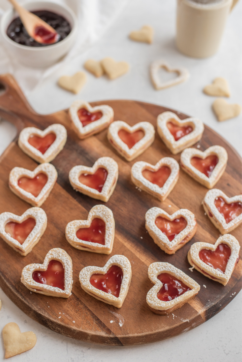 heart shaped raspberry linzer cookies on cutting board