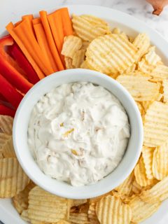 caramelized onion dip in bowl surrounded by chips and veggies