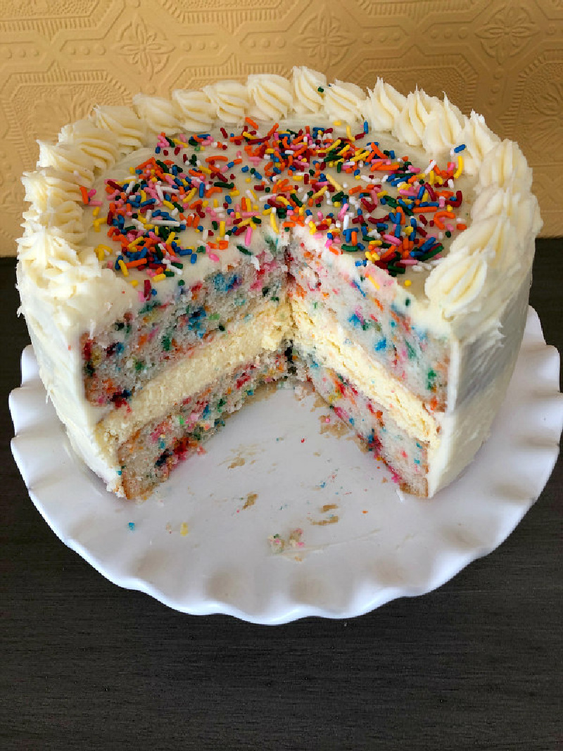 funfetti cheesecake cake on white cake stand