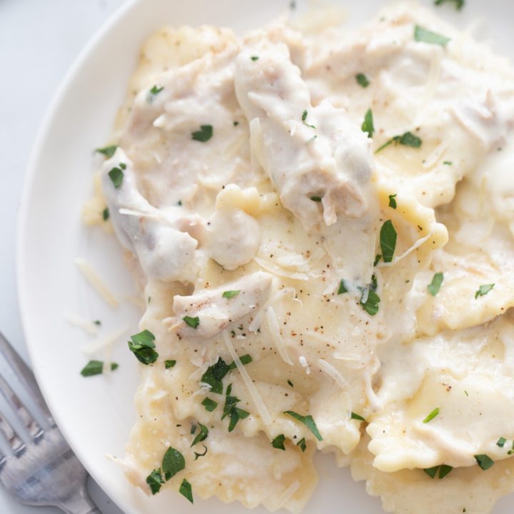 white plate with ravioli alfredo and chicken