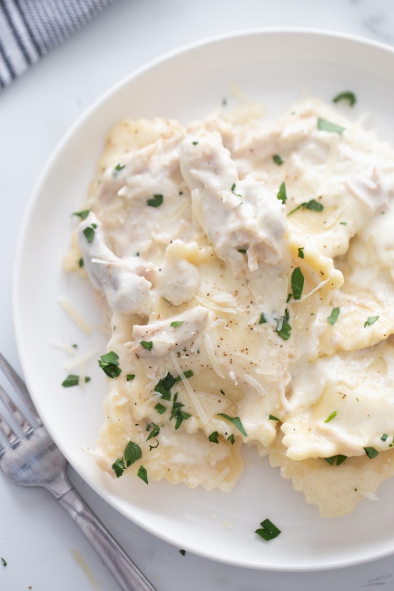 white plate with ravioli alfredo and chicken