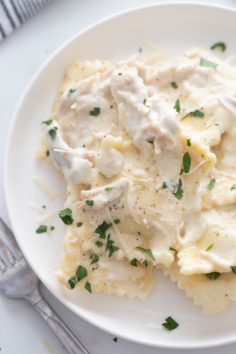 white bowl of ravioli with alfredo sauce and chicken