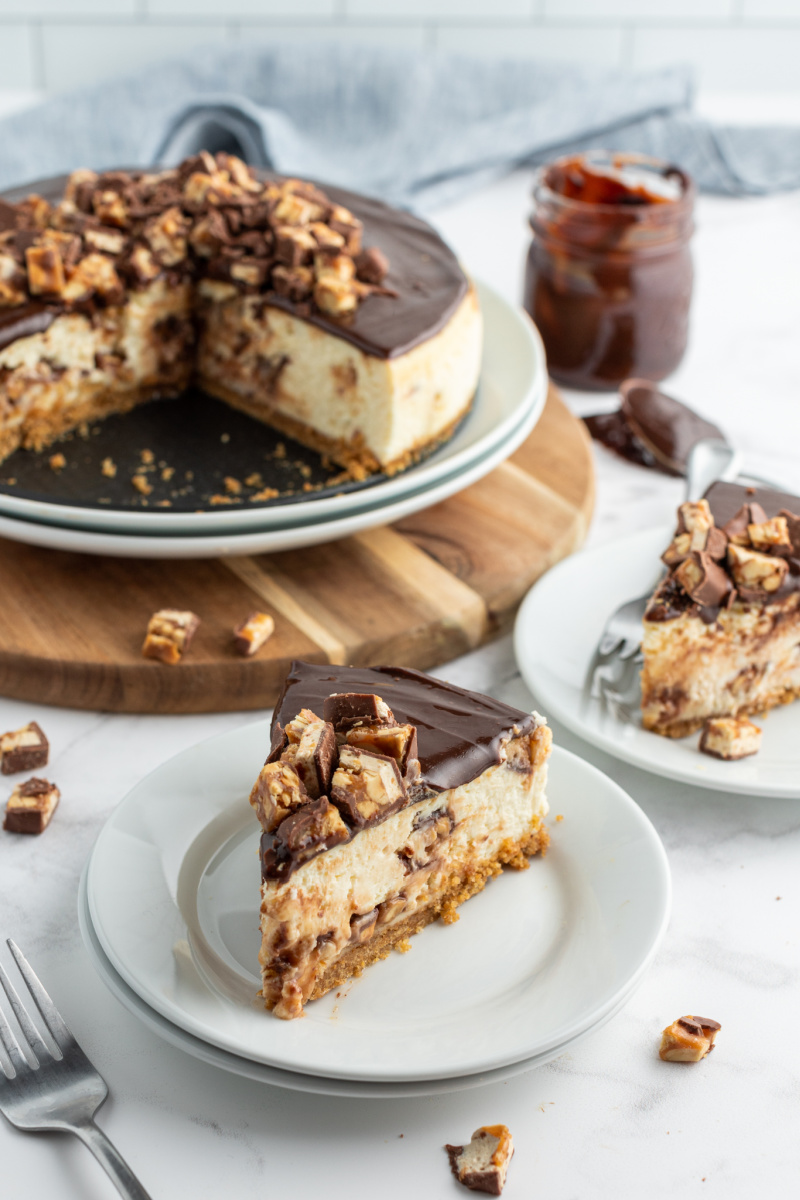 slice of cheesecake on a plate with whole cheesecake in background