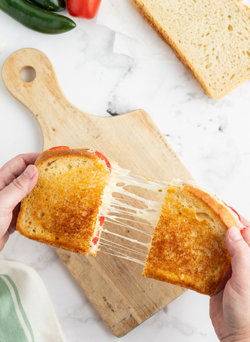 two hands pulling apart a grilled cheese sandwich to show melted cheese