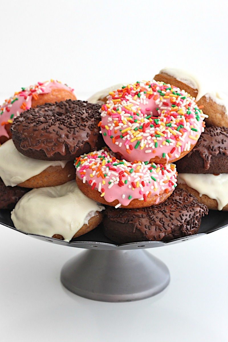 baked cake doughnuts with different color glaze on raised platter