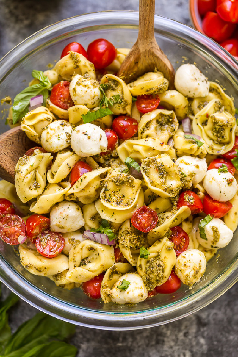 pesto tortellini salad in bowl with serving spoon