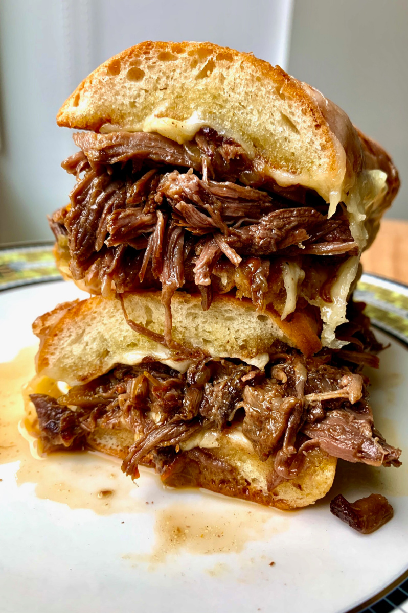 beef hoagie cut in half and stacked on white plate