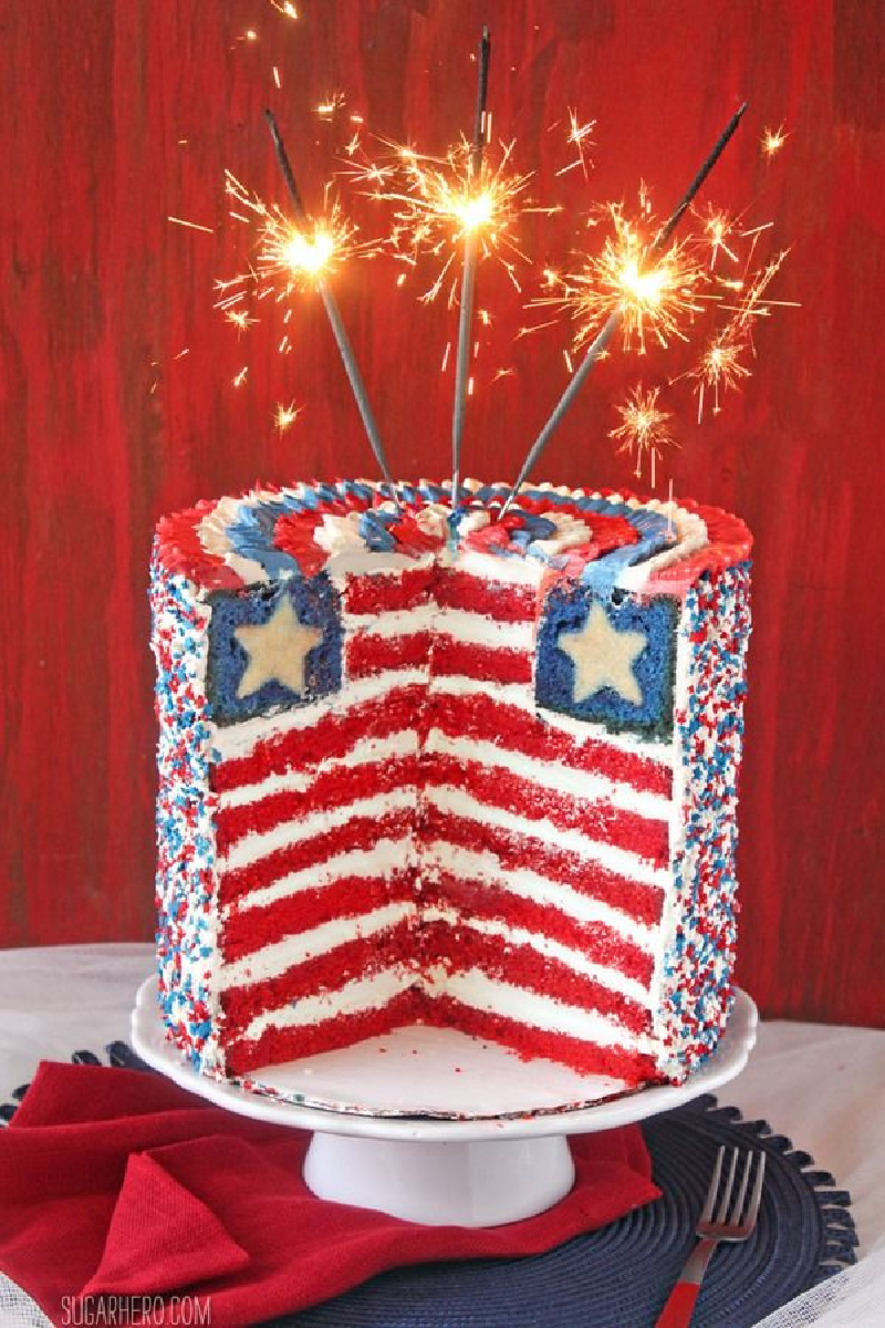 american flag layer cake sliced open with sparklers lit on top