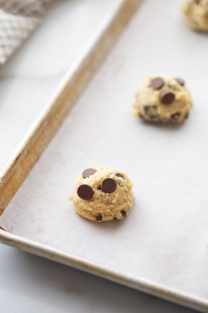 chocolate chip cookie dough on a baking sheet ready for oven