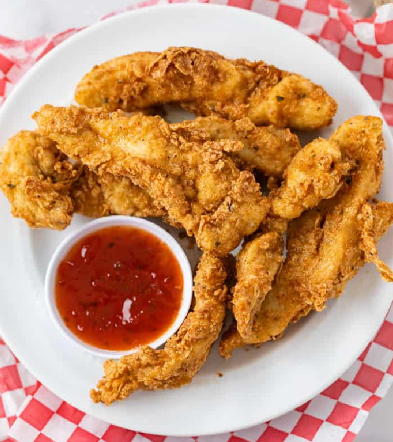 fried chicken tenders on a white plate with ketchup