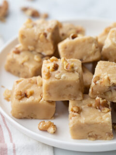 pieces of maple walnut fudge stacked on white platter