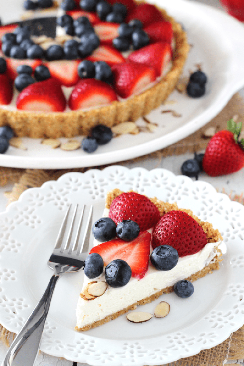 slice of berry almond tart with rest of tart displayed behind it