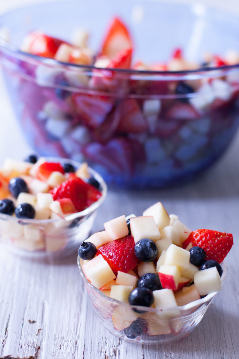 bowl of red white and blue fruit salad with two individual servings displayed