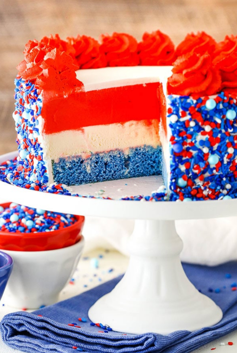 red white and blue ice cream cake on a white cake stand sliced open