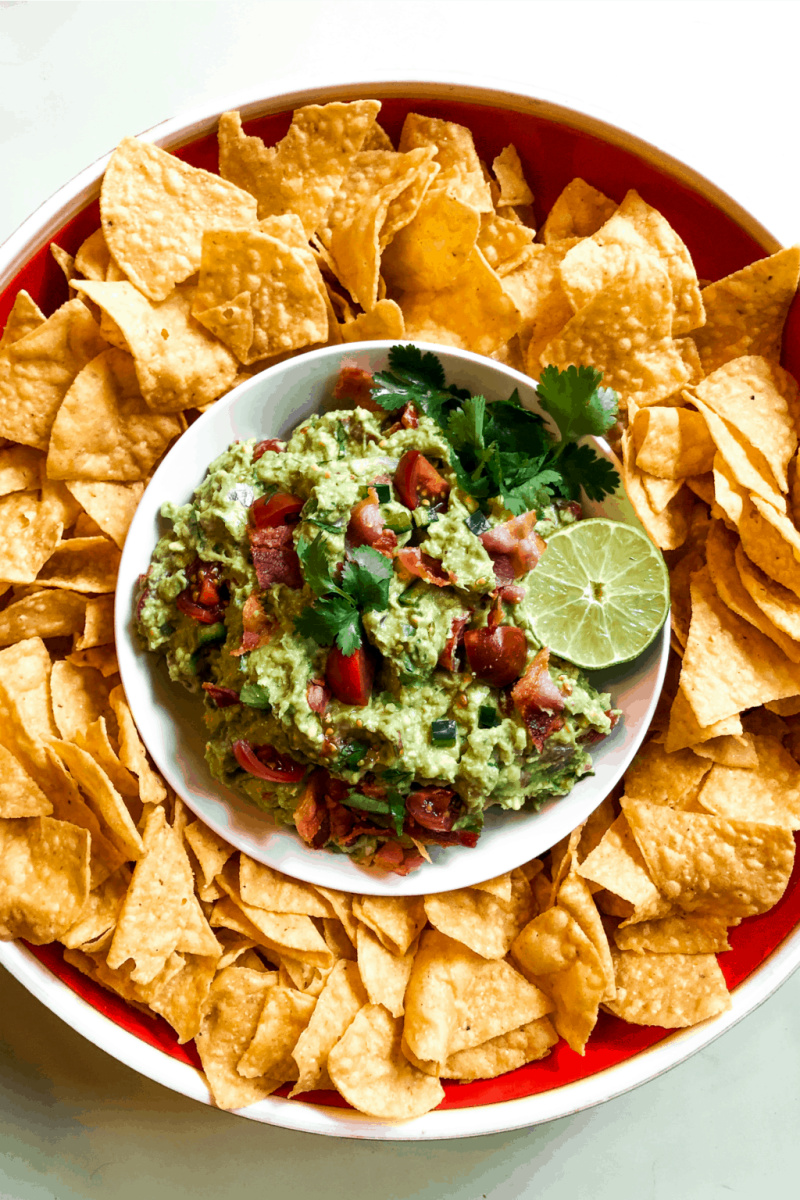 bacon guacamole in bowl surrounded by chips