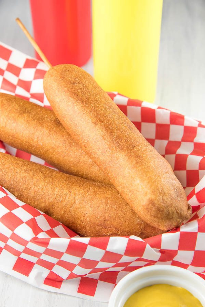 corn dogs in a basket lined with red and white checked paper