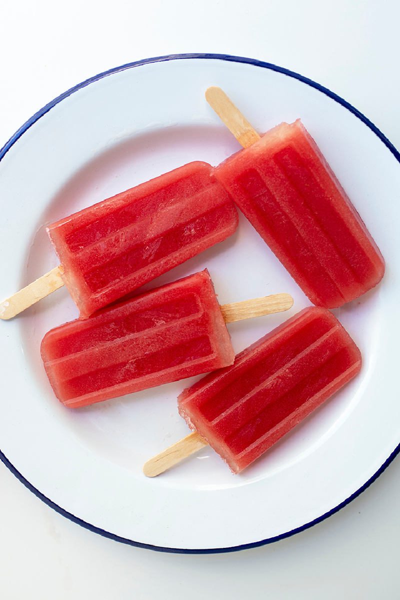 four watermelon popsicles on a white plate