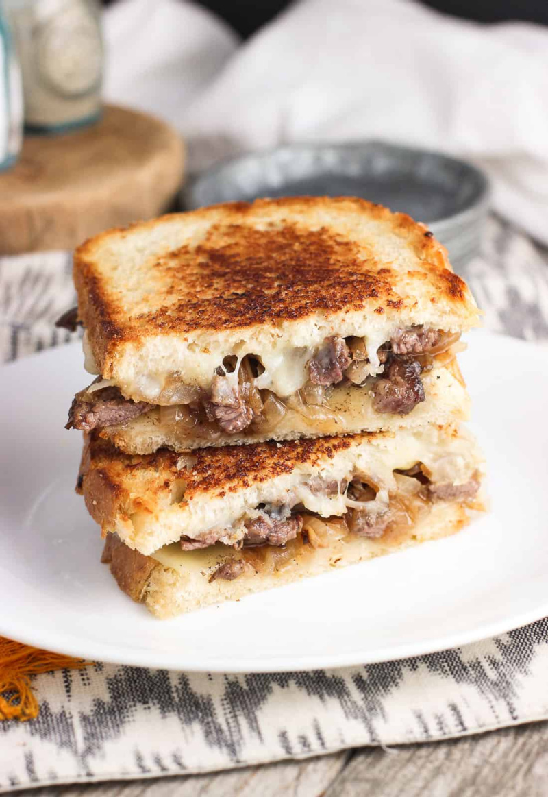 stacked philly cheesesteak panini on a white plate