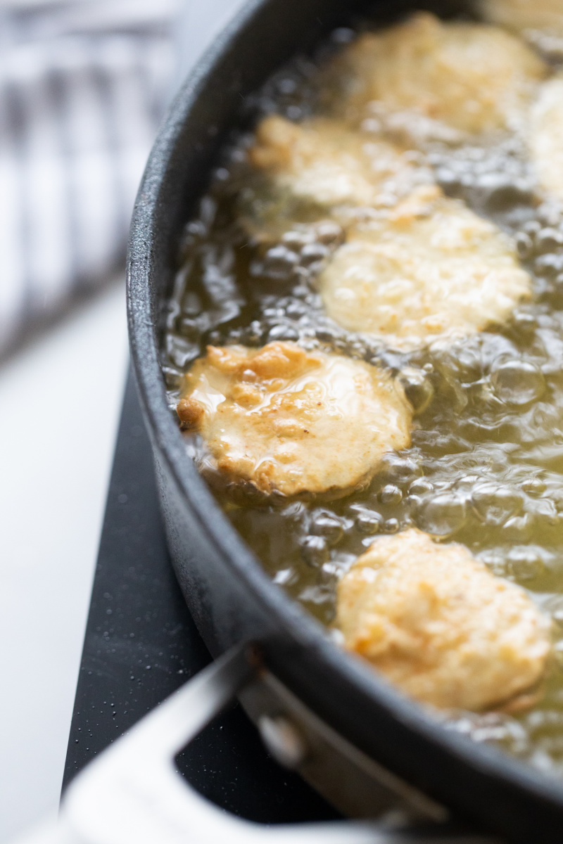 frying pickles in a pan of hot oil