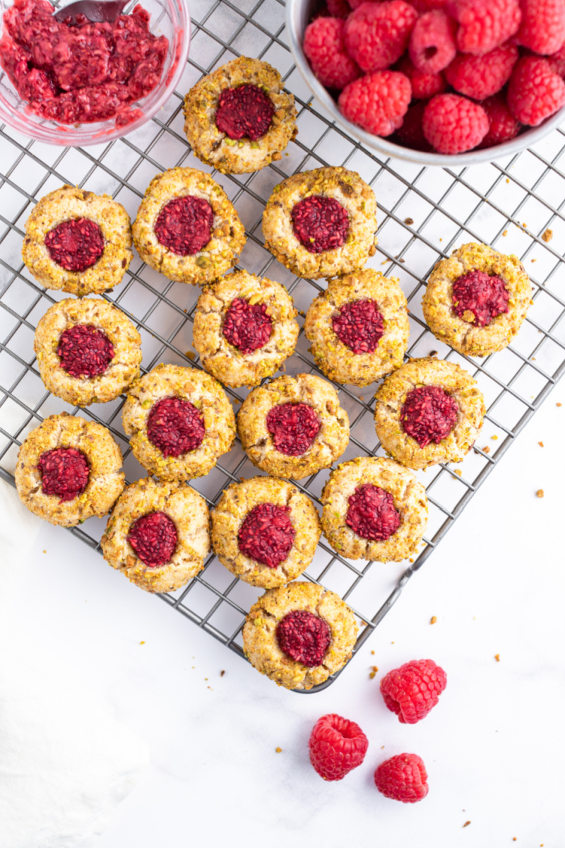 raspberry pistachio thumbprint cookies on a baking rack