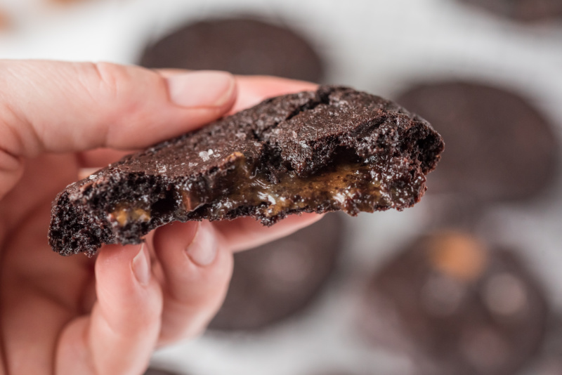 hand holding half a chocolate cookie to see caramel inside