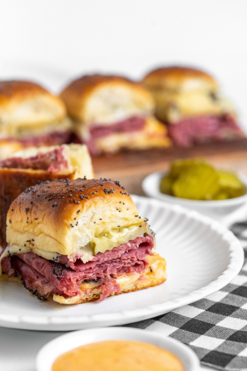 hot pastrami slider on white plate with other sliders in background