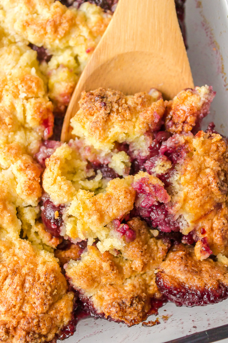 spooning cherry cobbler out of pan