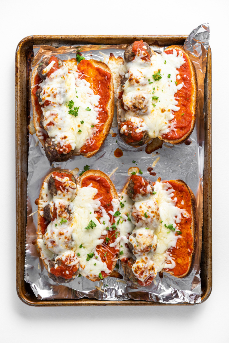 four meatball subs on a baking sheet
