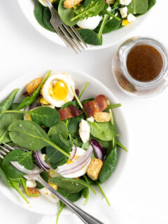 plate of spinach salad with dressing on side