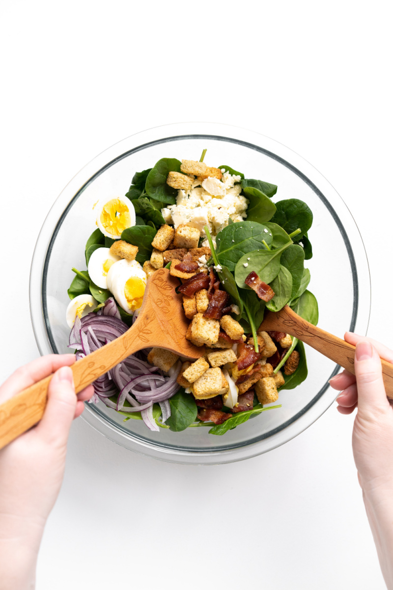 tossing spinach salad with salad tongs