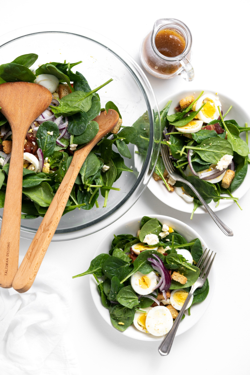 plating spinach salad from bowl of salad