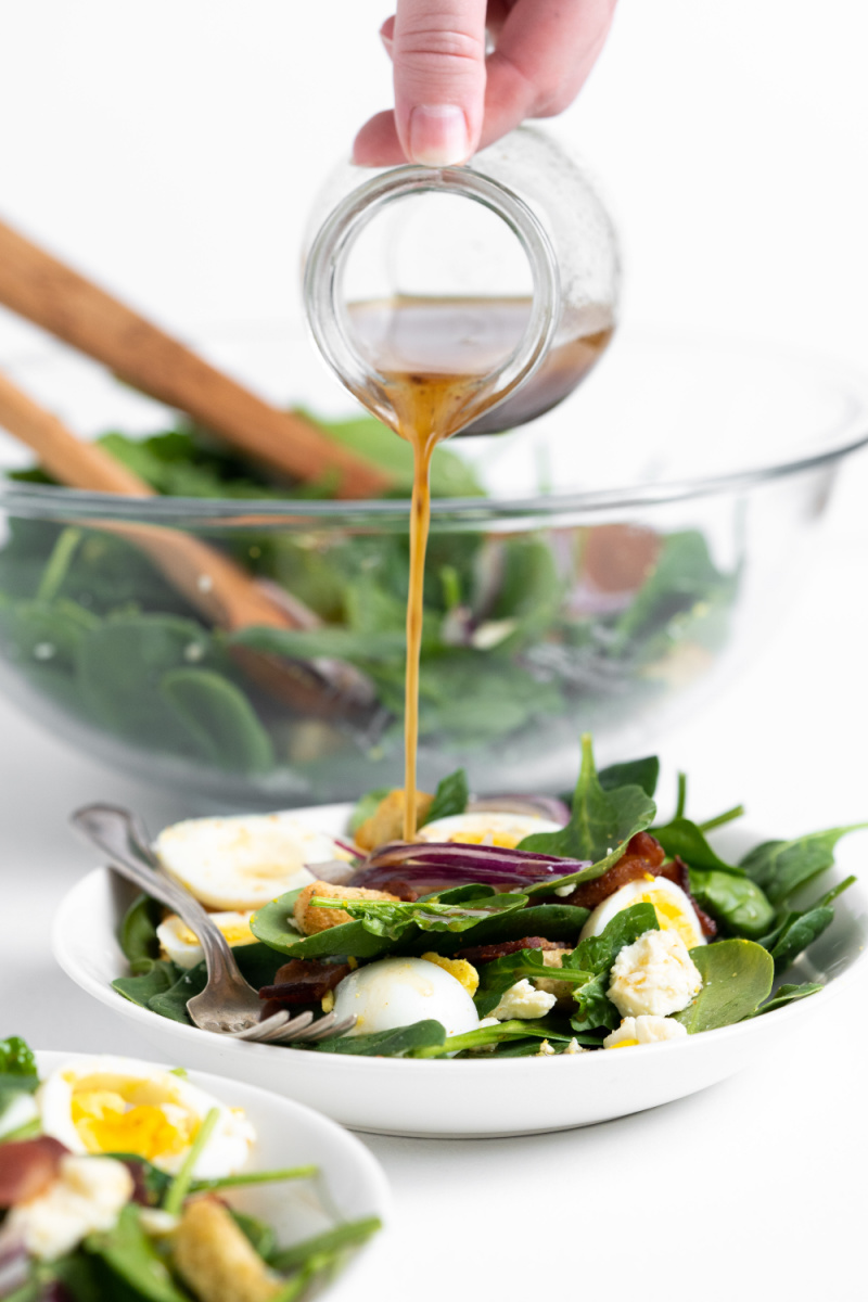 pouring dressing onto spinach salad
