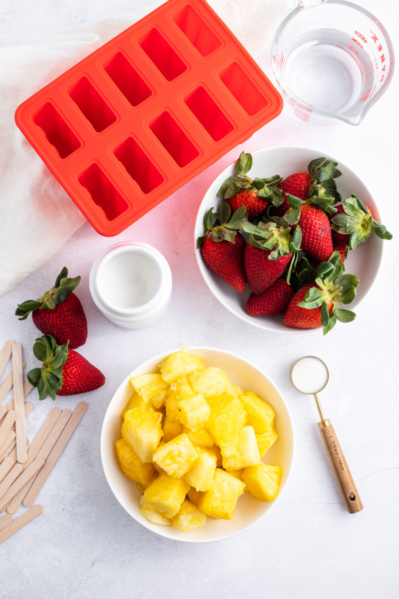 ingredients displayed for making strawberry pineapple popsicles