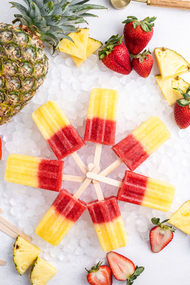 7 strawberry pineapple popsicles placed in a circle on ice