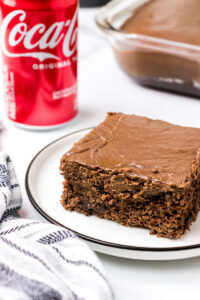 slice of coca cola cake on a plate with coke in background