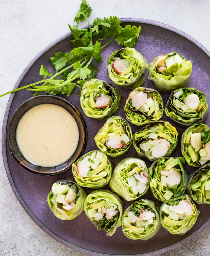 lobster spring rolls on a platter with dipping sauce