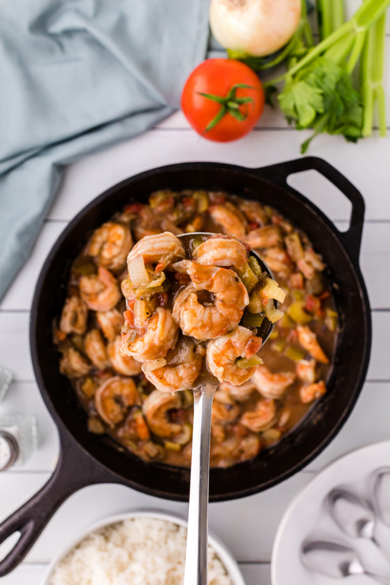 spooning shrimp gumbo out of cast iron skillet