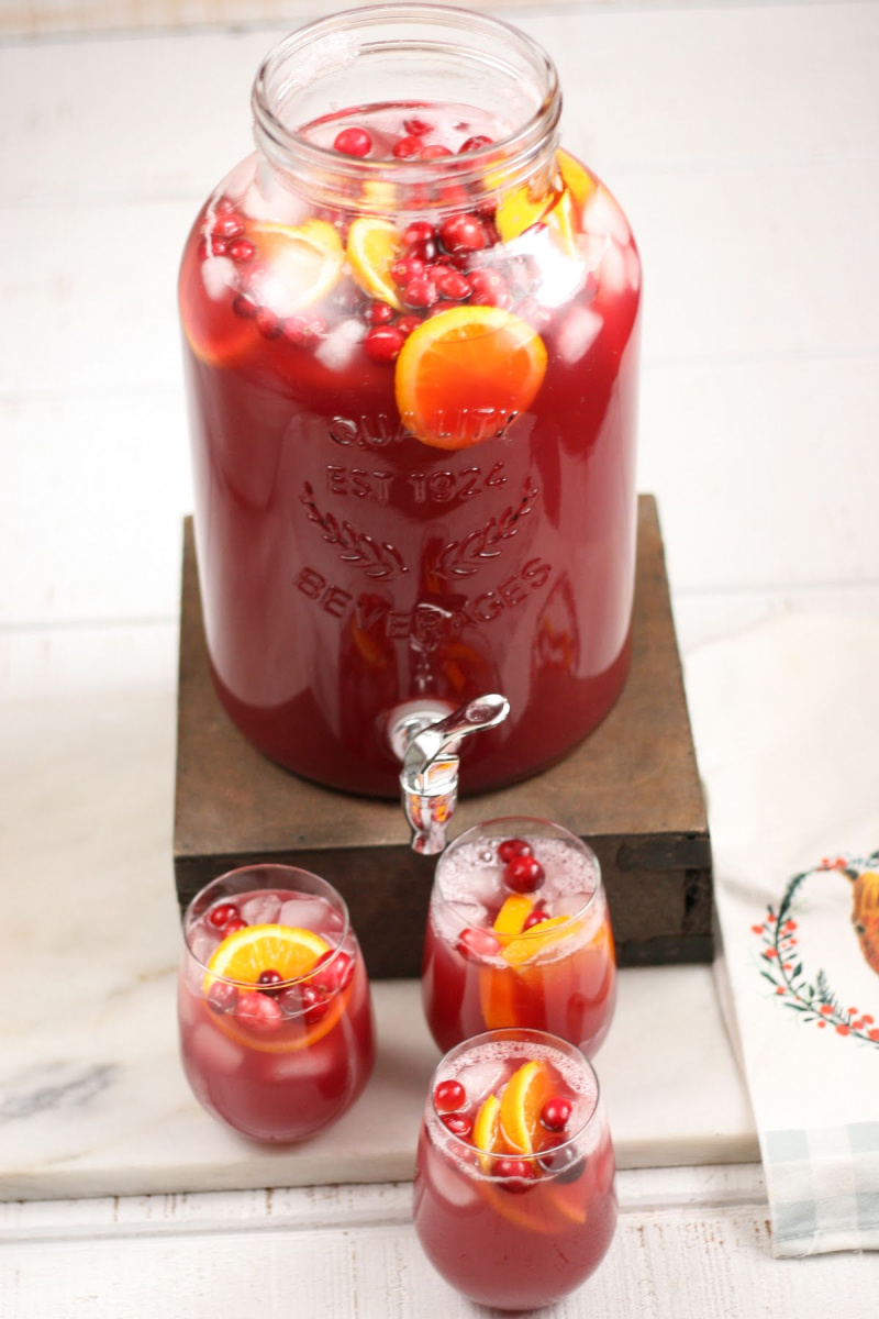 glass container of holiday punch with two glasses