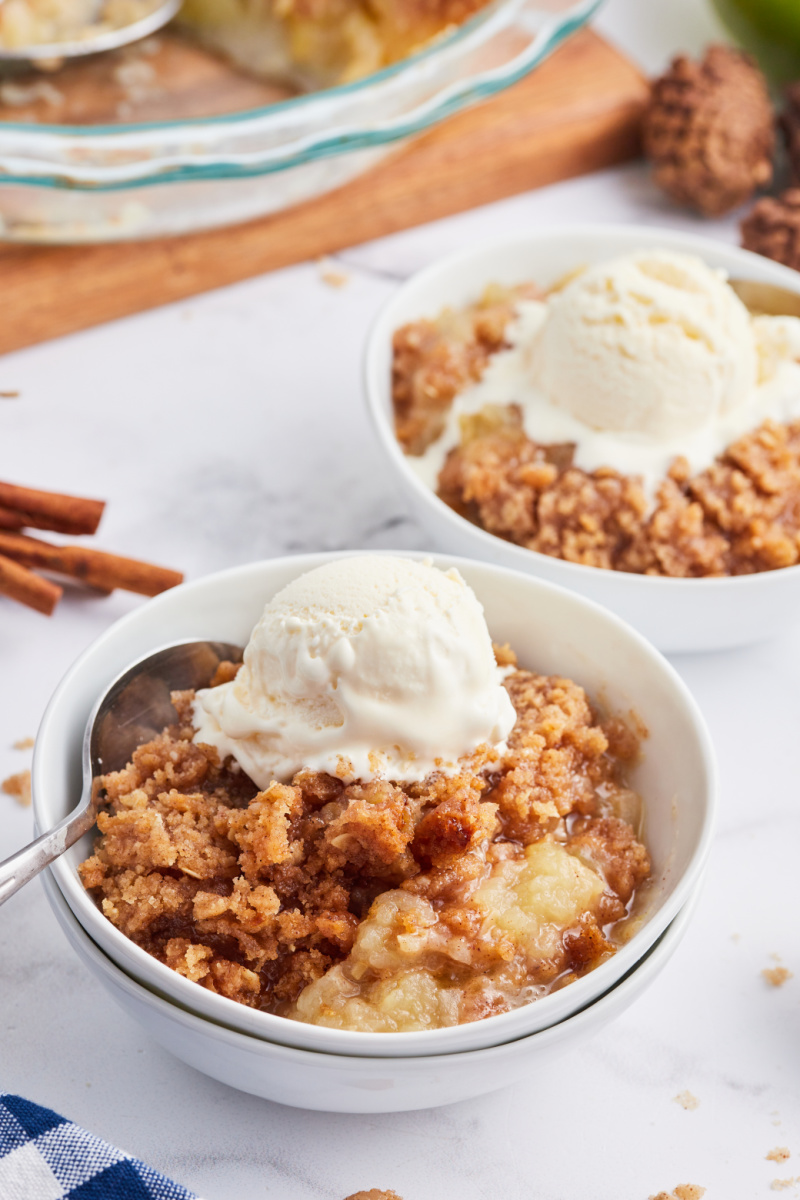 two servings of apple betty in bowls with vanilla ice cream