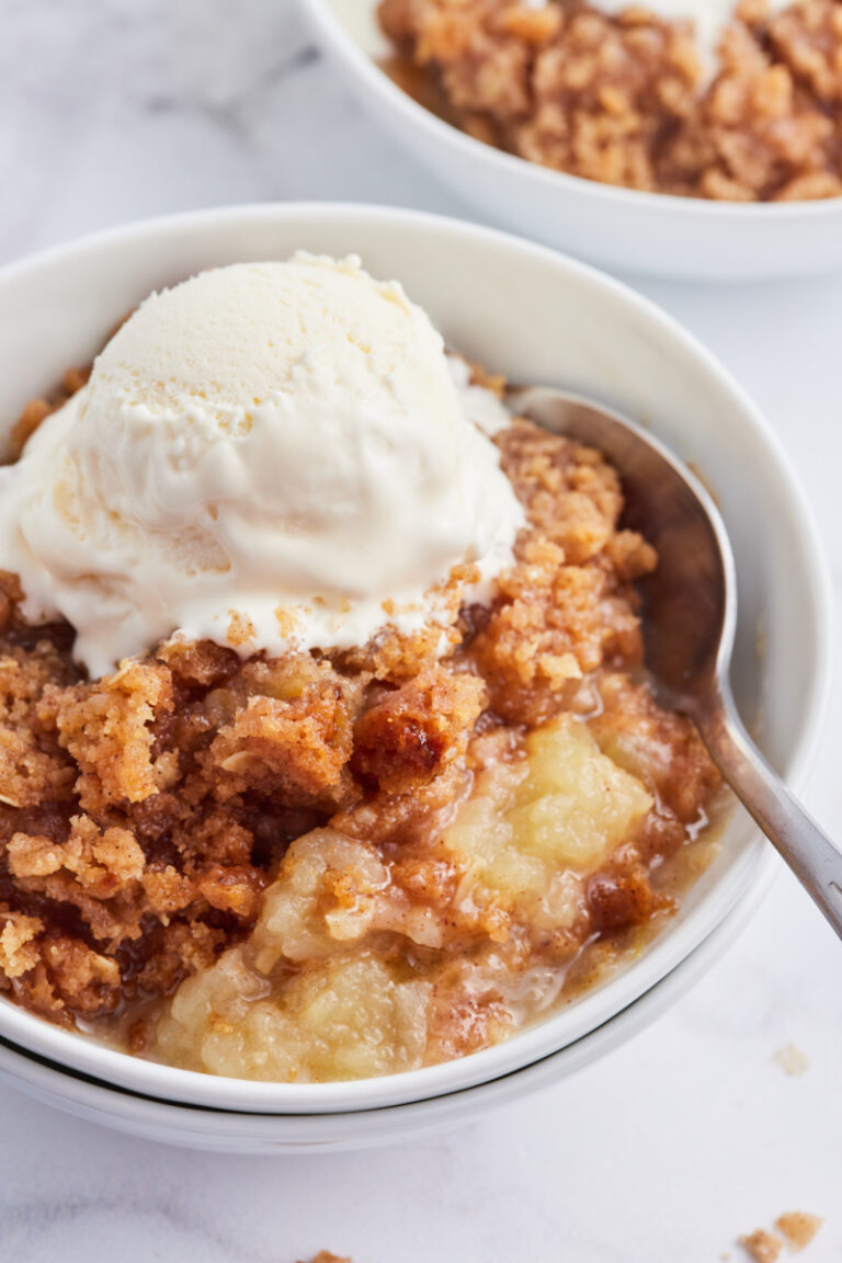 apple betty in a bowl topped with vanilla ice cream