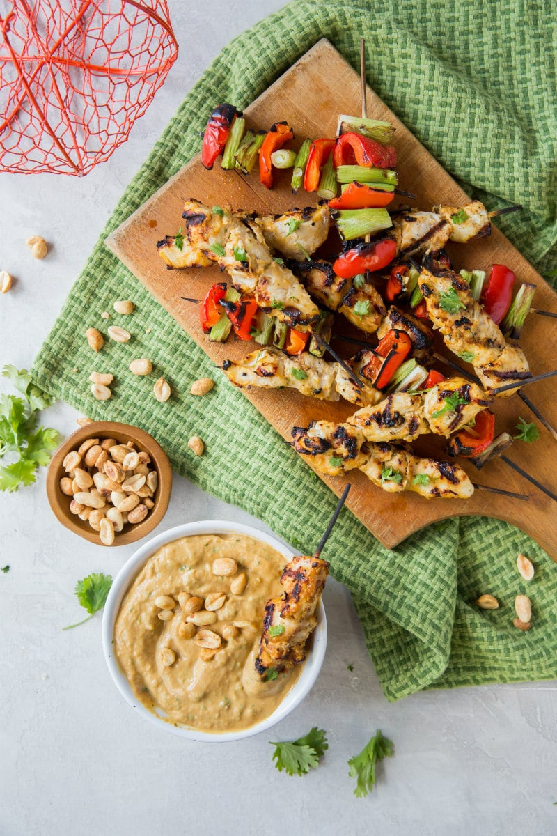 thai pumpkin chicken satay skewers on a board with sauce