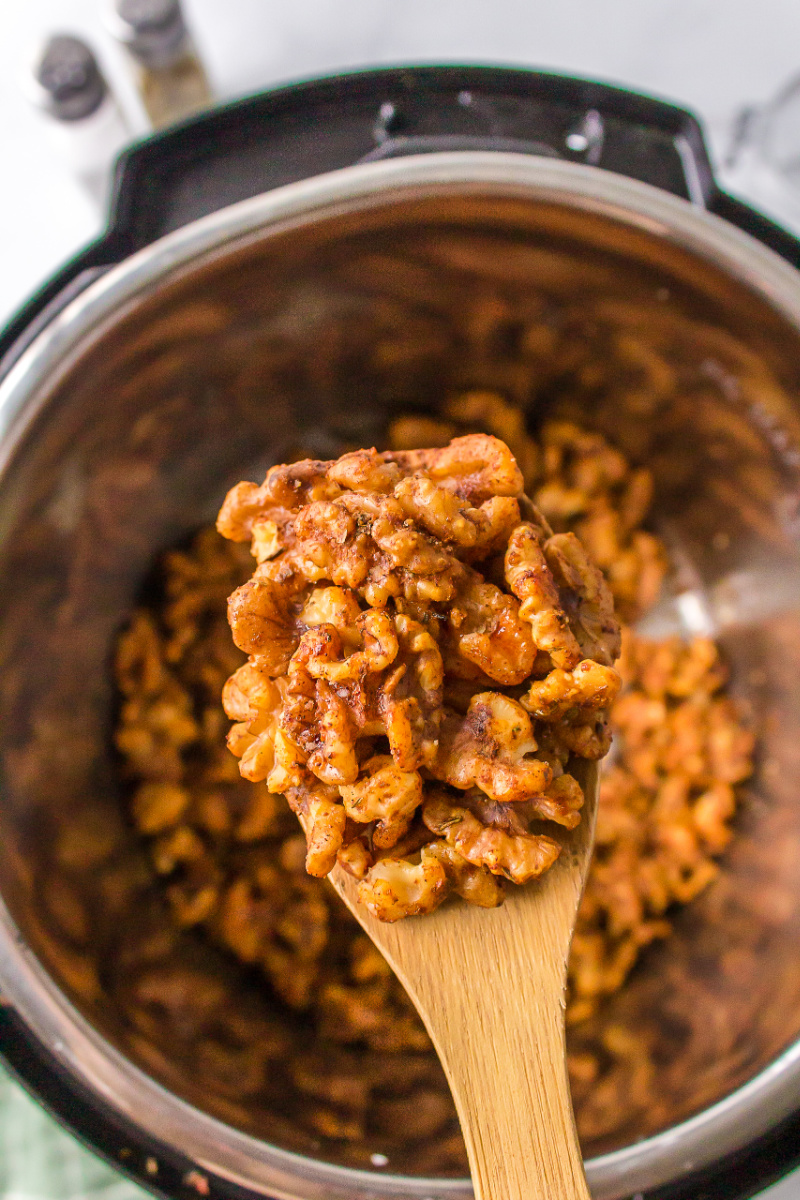 wooden spoon with cajun spiced walnuts on it over instant pot