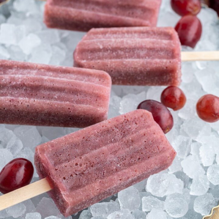 four grape popsicles sitting on ice