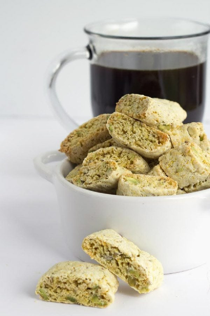orange pistachio biscotti in bowl with cup of coffee